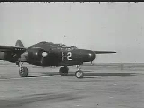 TWA airliner and military aircraft parked on tarmac.