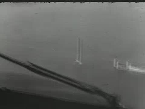View from cockpit window flying over water toward land.