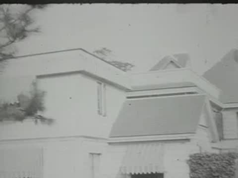 Panning shot of houses and a blimp floating in the sky.