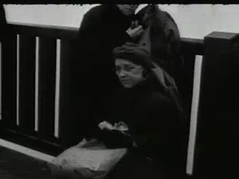 woman sitting outdoors wearing a headscarf and dark coat