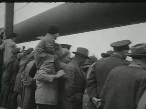 crowd of people gathered together outdoors near a railing