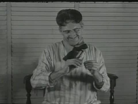 smiling man in striped pajamas sitting indoors and adjusting his collar