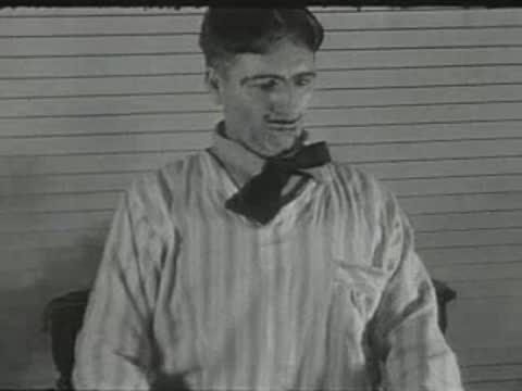 man in striped pajamas sitting indoors and adjusting his clothing