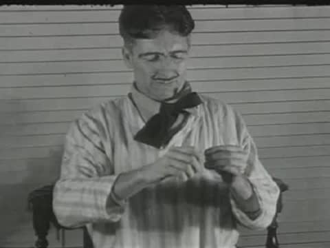 smiling man in striped shirt sitting indoors and adjusting his collar