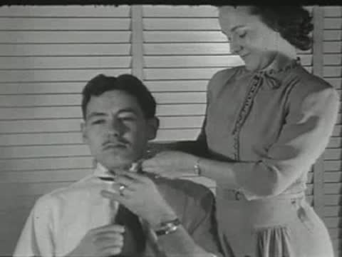 woman fixing a man's tie and hair indoors