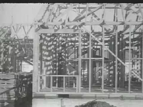 The wooden frame of a house under construction on a dirt lot.