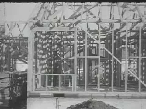 The wooden frame of a house under construction on a dirt lot.