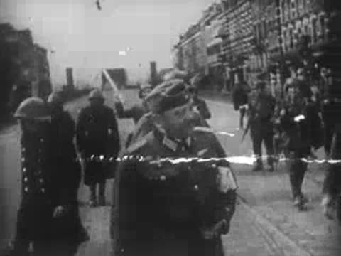 German military officers walking down a city street in World War II uniform.