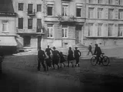 people walking down a city street with a cyclist in the 1940s