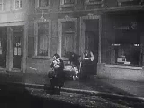 man holding a child and woman pushing stroller on city street