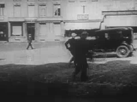 civilians walking on a cobblestone street before and after an explosion