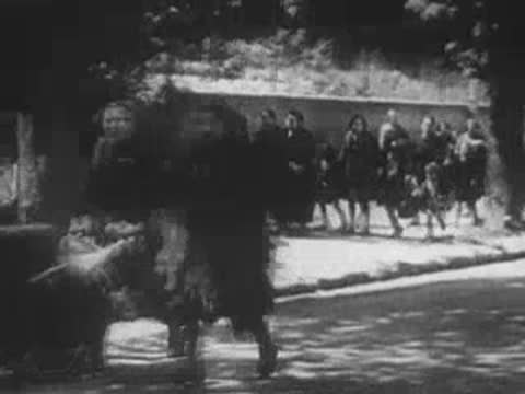 women pushing carts and walking on a tree-lined street during wartime