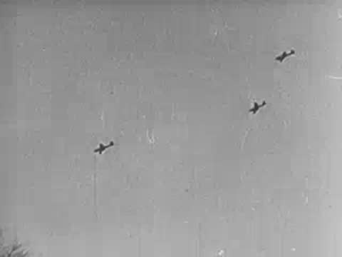 soldiers taking cover in a field as airplanes fly overhead in formation