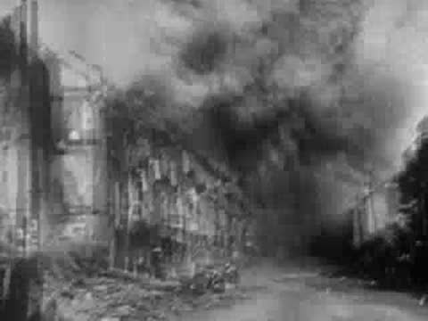 German Stuka dive bombers attack, billowing thick black smoke over buildings.