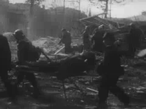 Workers carry a stretcher with an injured person through bombed-out ruins.