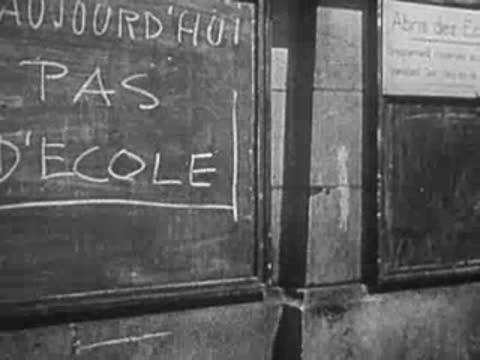 Debris in street near building with blackboard reading "AUJOURDHUI PAS DECOLE".