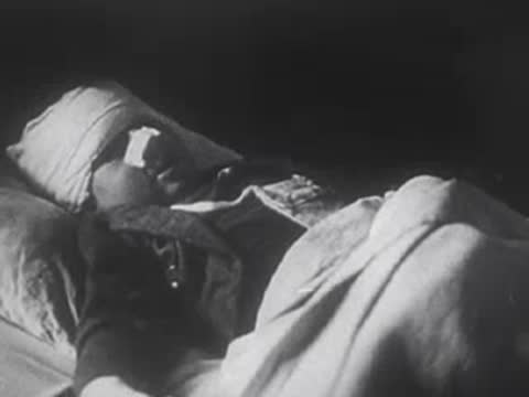 Injured child with heavily bandaged head rests sleeping in a hospital bed.