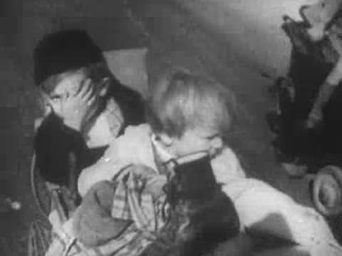Distressed children cover their faces and hold each other outdoors.