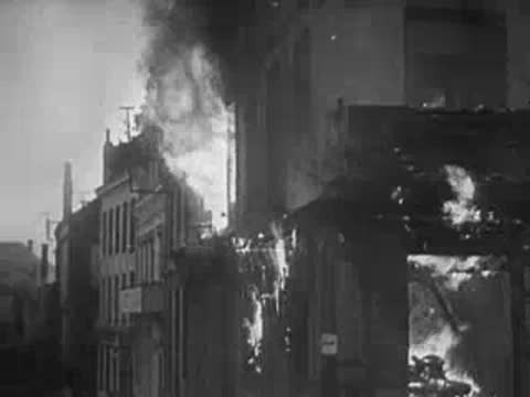 Buildings heavily damaged by fire with thick smoke pouring out.