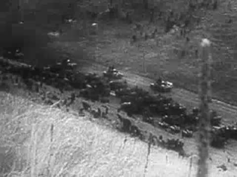 Aerial view of military transport vehicles stalled on a rural road.