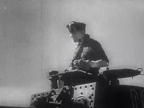 Soldier in uniform standing in open-topped military vehicle against sky, World War II