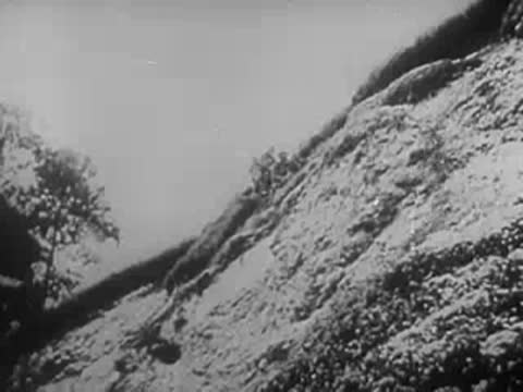 Steep grassy hillside with vegetation under an overcast sky, World War II