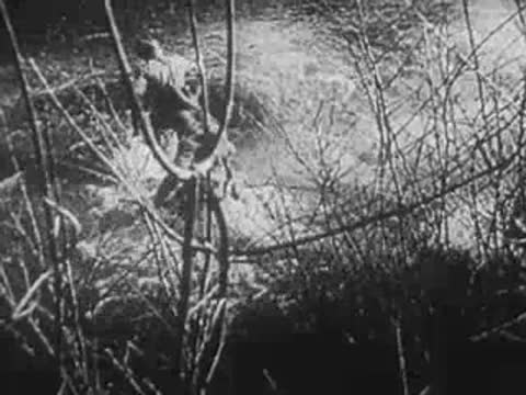Soldier navigating through a muddy trench with barbed wire, World War II