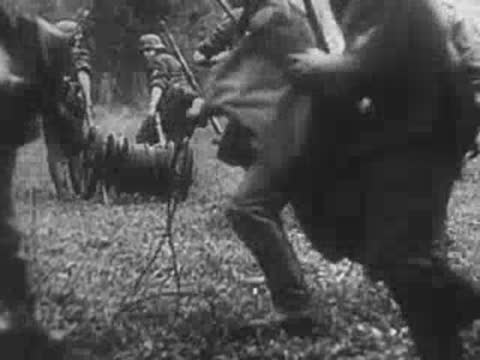 Soldiers operating field artillery equipment and pulling cables in a forest, World War II