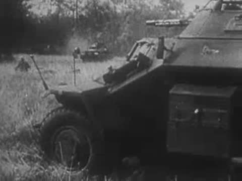 A German armored car parked in a field with soldiers positioned nearby.