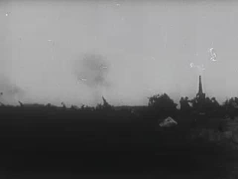 Artillery firing in a field and a close-up of a tank with a diamond marking.