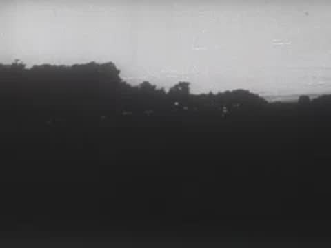 Dark horizon silhouettes under a dim sky with faint flashes of light.