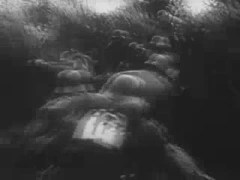 German soldiers advancing forward through a field in combat gear.