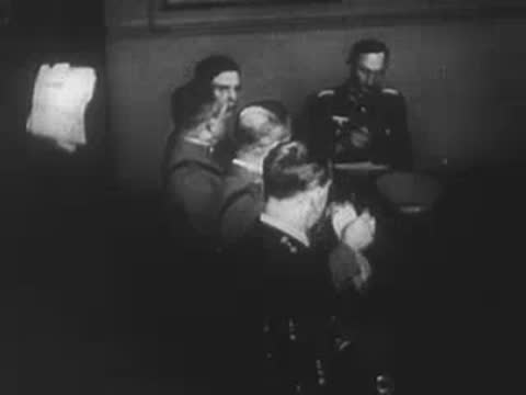 German soldiers entering a building and conferring at a table inside.