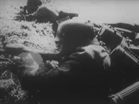 German machine gunner aiming and firing from a fortified position.