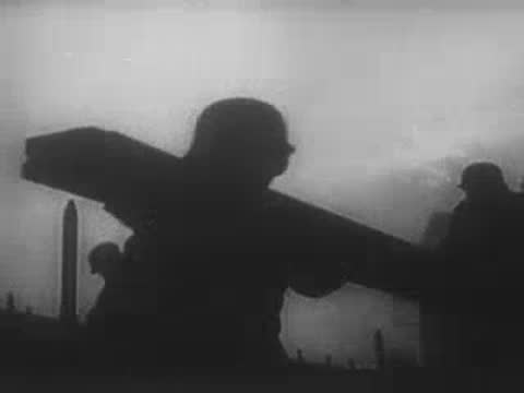 Soldier carrying a heavy plank across a bridge in haze.