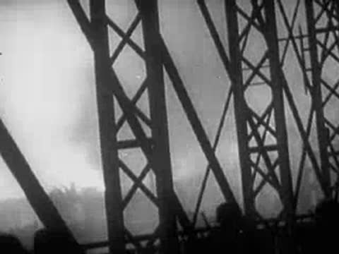 Steel bridge framework with silhouetted figures watching from below.