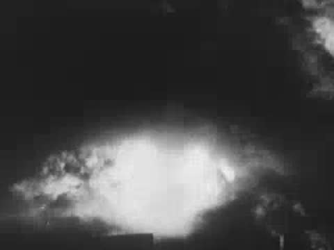 Heavy nighttime explosions lighting up clouds of smoke during a bombing raid, WWII