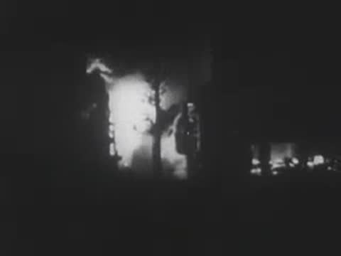 Flames engulfing residential buildings at night during a wartime bombing, WWII