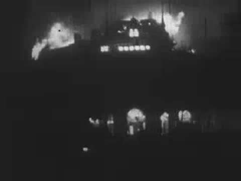 Flames raging inside a multi-story building through shattered windows at night, WWII