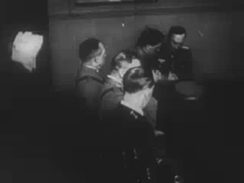 German officers studying maps and documents around a table indoors.