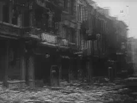 Ruined buildings with debris covering the sidewalk and street after a bombing, WWII