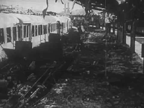 Railroad tracks covered in debris with parked passenger rail cars nearby, WWII