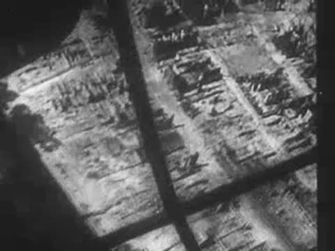 Aerial view of a heavily bombed and burned city grid from an aircraft window, WWII
