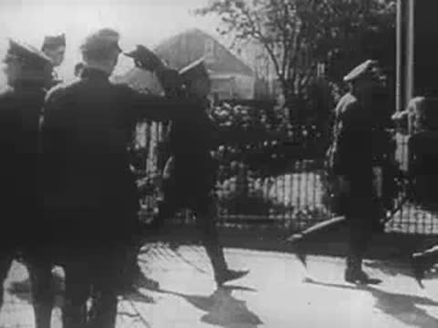 German officers walking outdoors, saluting as they pass by.