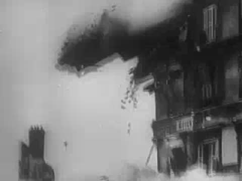 Explosion and smoke rising amidst damaged buildings during wartime.