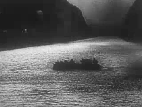 Small boat moves across water under smoke, archive footage