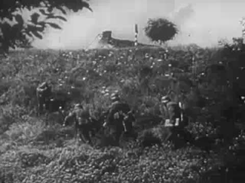 Soldiers with equipment advance past a embankment, archive footage