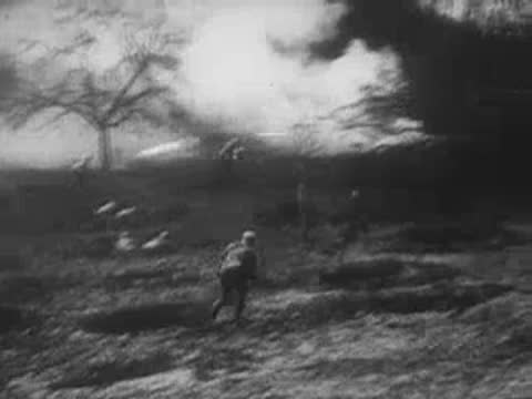 Soldiers advance across a field with smoke, archive footage