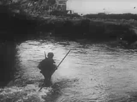Soldier poling a small boat across a river, WWII archival footage.