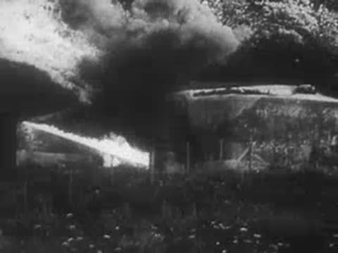 Explosion and smoke emerging from a concrete bunker, WWII era.